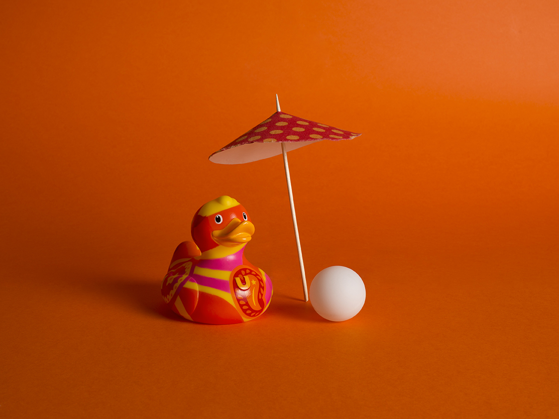 photographie d'un canard en plastique avec son parasole et sa balle