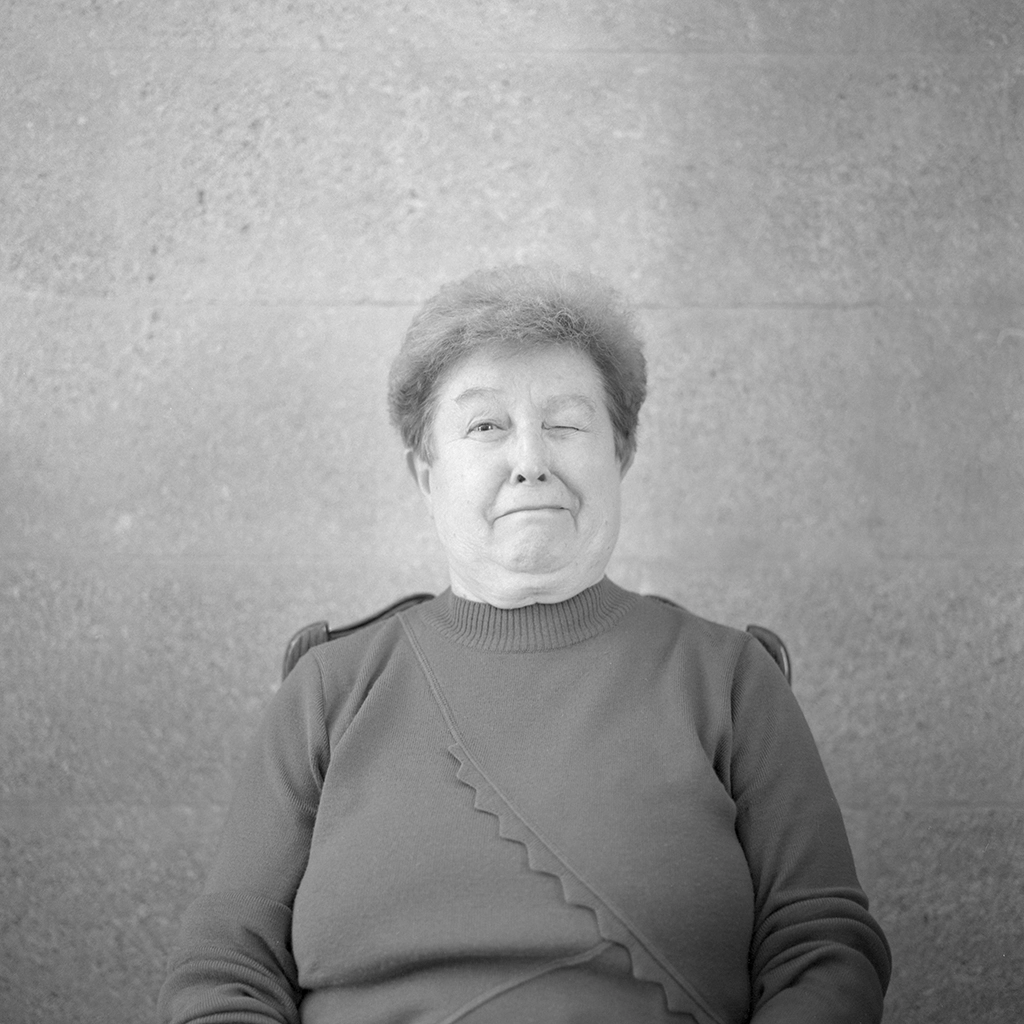 Portrait argentique en format carré en noir et blanc d’une vieille femme faisant une grimace