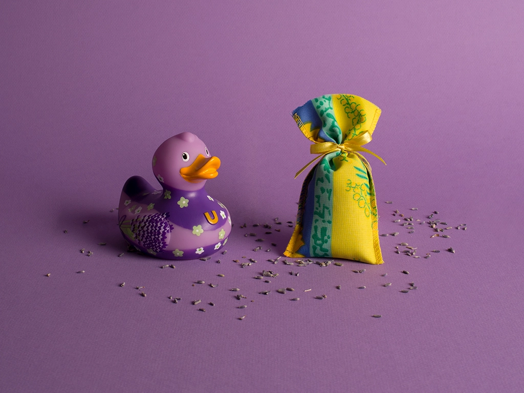 Canard en plastique couleur lavande avec son petit paquet de lavande séchée sur fond lavande